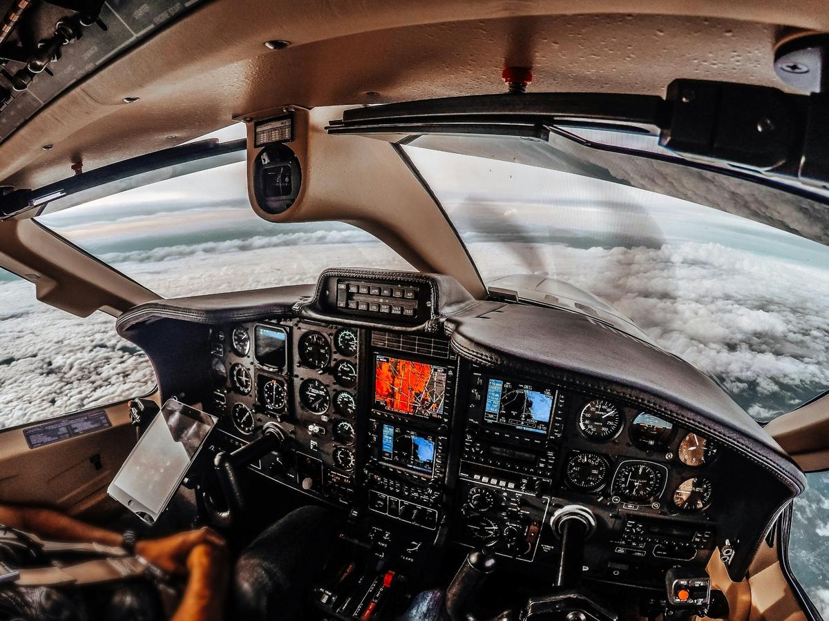 Small plane cockpit flying above a sea of clouds