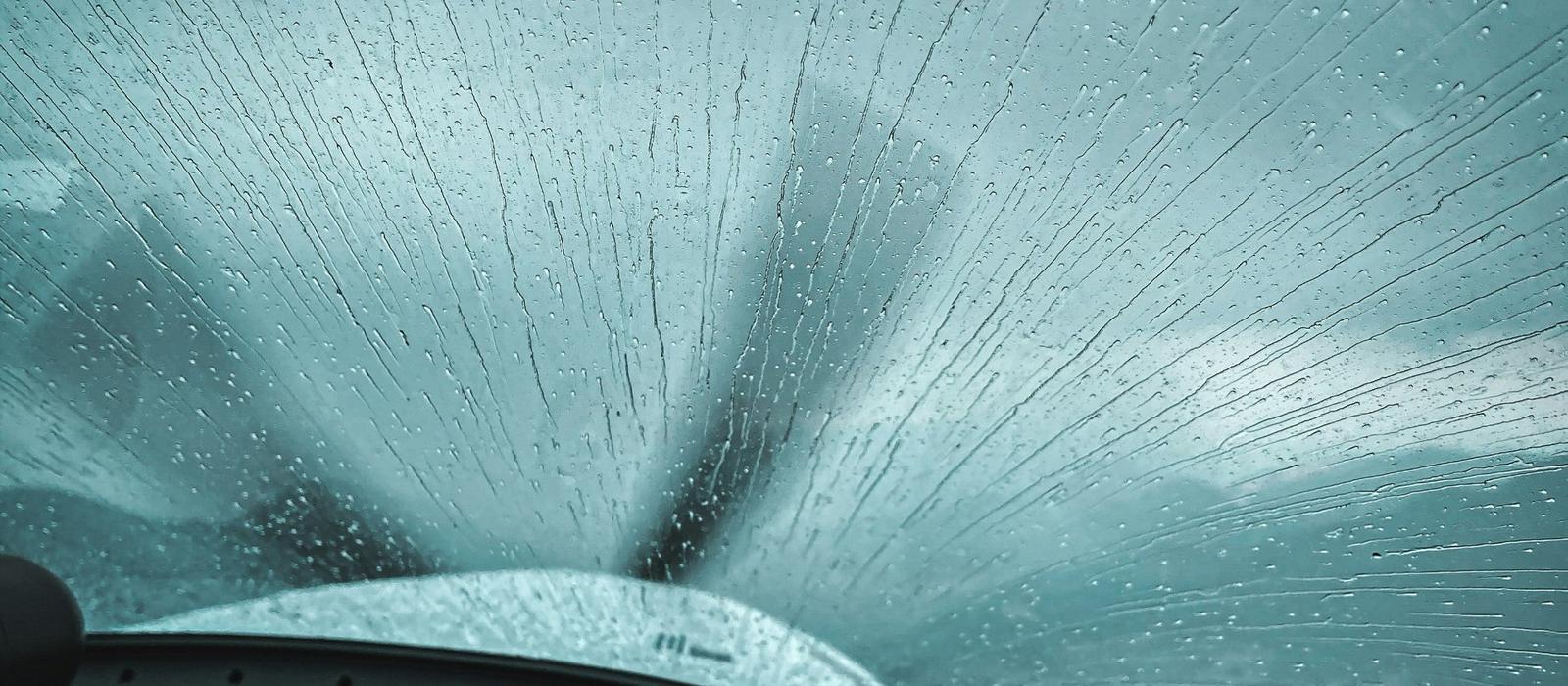 Rain streaking across a small plane windshield above the instrument panel